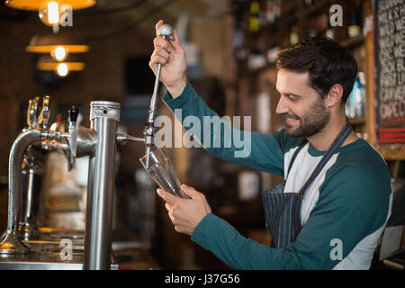 Glücklich Barkeeper Gießen Bier vom Fass im Glas in Bar Stockfoto