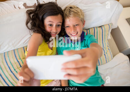 Geschwister unter Selfie auf Handy im Schlafzimmer zu Hause Stockfoto