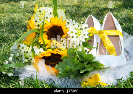 Brautstrauß von Wildpflanzen, Geranien, Sonnenblumen und Brautschuhe Stockfoto