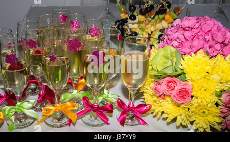 Festlich gedeckten Tisch. Glas Sekt mit Bändern geschmückt. Blumenstrauß. Frucht-snacks Stockfoto