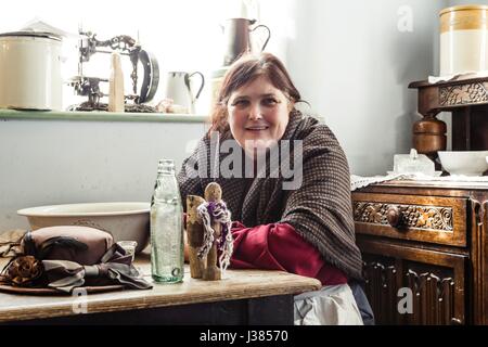 Eine Frau posiert in Victorian Kleid in der Hausbesetzer-Hütte im Blists Hill Museum, Ironbridge, UK Stockfoto