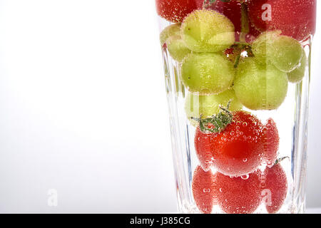 Cherry-Tomaten und Trauben in ein Glas mit Waterwith Textfreiraum. Stockfoto