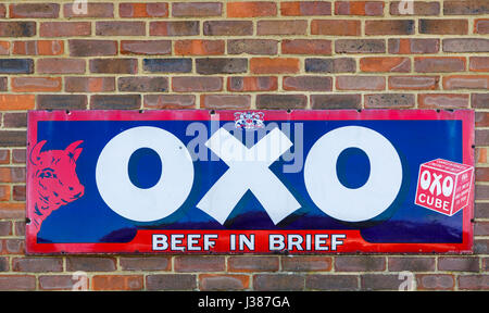 Old-fashioned, Vintage metallisches Zinn Werbung für OXO-Würfel auf eine Mauer bei Tenterden Town Station, Tenterden, Kent, Süd-Ost-England, UK Stockfoto