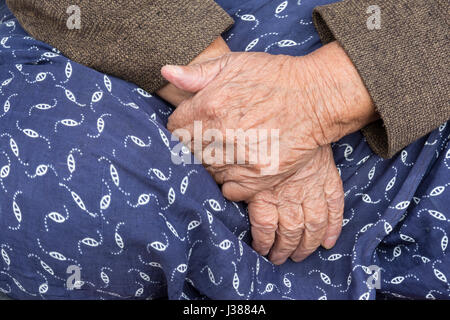 Die ältere Frau Hände, ein Detail einer alten Frau die Hände auf traditionelle Rock. Stockfoto