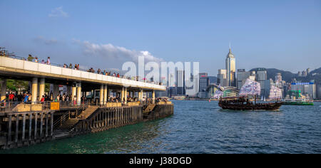 Touristen an der Tsim Sha Tsui Promenade und der neu gestalteten Drachen traditionelle chinesische Dschunke, Victoria Harbour, Hong Kong, China. Stockfoto