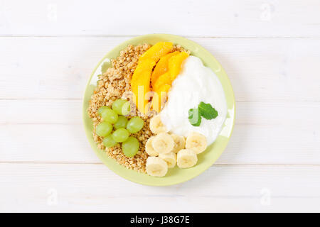 Teller mit Müsli mit Joghurt und frischem Obst auf weißem Hintergrund Stockfoto