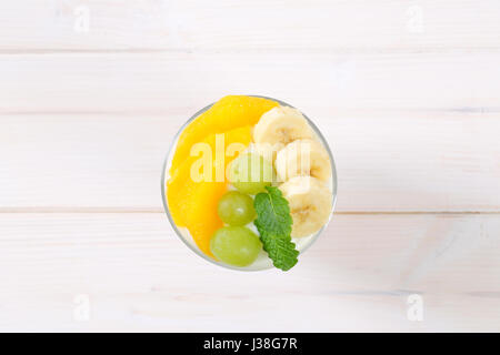 Glas aus Müsli mit Joghurt und frischem Obst auf weißem Hintergrund Stockfoto