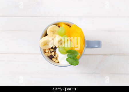 Tasse Müsli mit Joghurt und frischem Obst auf weißem Hintergrund Stockfoto