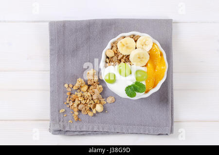 Schüssel mit Müsli mit Joghurt und frischem Obst auf grauen Tischset Stockfoto