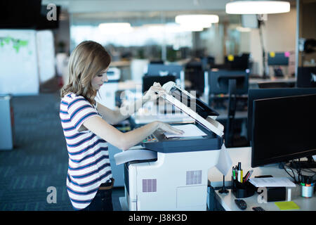 Seitenansicht der junge Geschäftsfrau mit Kopierer im Büro Stockfoto