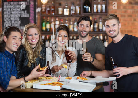 Porträt von Freunden, die Pizza mit Bier im restaurant Stockfoto