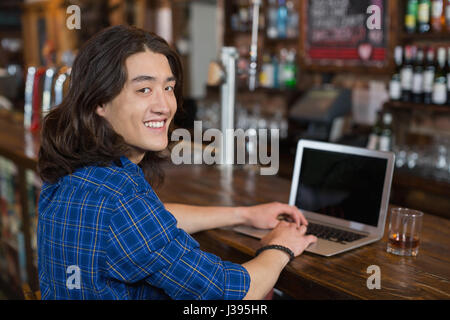 Porträt von lächelnden jungen Mann mit Laptop an der Theke Stockfoto