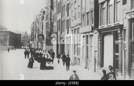 Dieser Blick auf den Damrak mit Blick auf den Dam-Platz in Amsterdam bietet eine Buchhandlung, die einen Moment des städtischen Lebens im 19. Jahrhundert in den Niederlanden festhält. Stockfoto