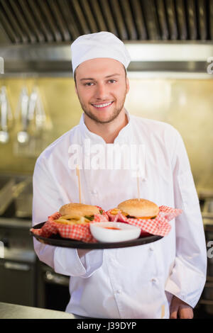 Porträt von Profi-Koch holding Burger in Platte Stockfoto