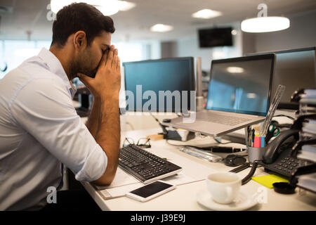 Nervösen Geschäftsmann am Schreibtisch im Büro Stockfoto