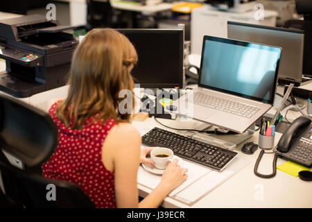 Erhöhte Ansicht der Geschäftsfrau Kaffeetrinken während der Arbeit im Büro Stockfoto