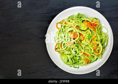 Low-Carb Zucchini Nudel-Gericht mit Karotten und Kalk auf dunklem Schiefer, Draufsicht Stockfoto