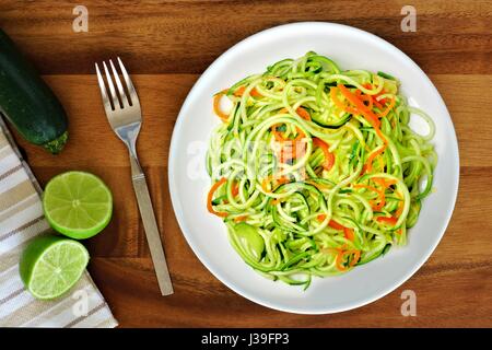 Gesunde Zucchini Nudel-Gericht mit Karotten und Kalk auf Holz Hintergrund, Draufsicht Stockfoto