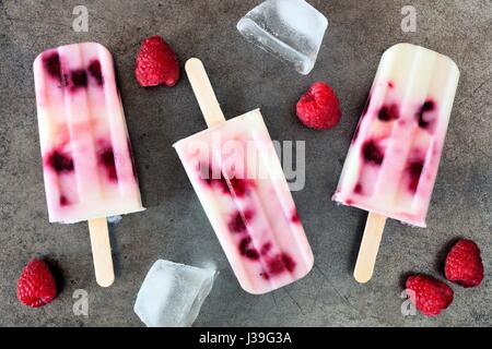 Hausgemachter Himbeer-Vanille-Eis erscheint auf einem rustikalen Metalltablett mit frischen Beeren Stockfoto