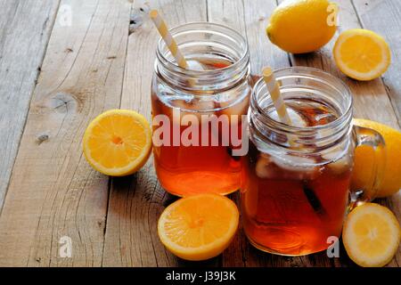 Zwei Mason Jar Gläser hausgemachte Zitrone Eistee auf einem rustikalen hölzernen Hintergrund Stockfoto