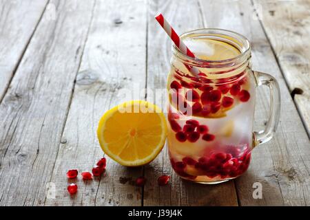 Granatapfel-Lemon detox Wasser in ein Einmachglas mit Stroh gegen einen rustikalen Holz Hintergrund Stockfoto