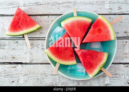 Wassermelone Stück Eis am Stiel auf einem Vintage blaue Platte und rustikale Holz Hintergrund Stockfoto