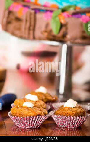 Leckeren braunen farbigen Muffins mit Karamell-Sauce und Sahne-topping, bunte Kuchen im Hintergrund, Gebäck-Konzept Stockfoto