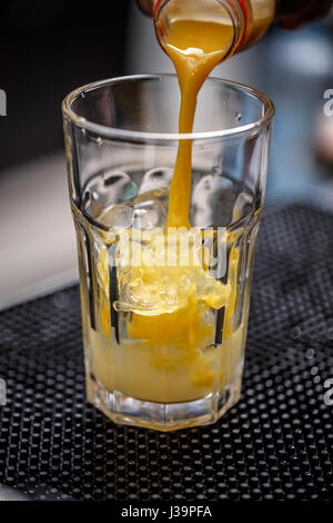 Closeup Aufnahme der Barkeeper gießt Getränk in ein Glas auf der Theke. Stockfoto