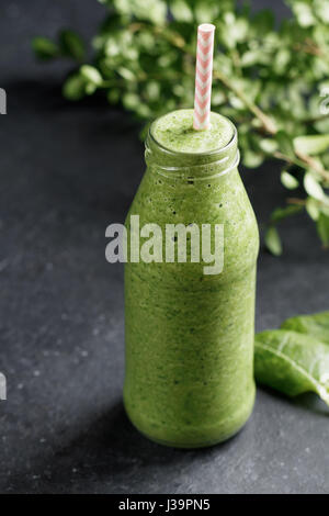 Glasflasche mit grünen Spinat detox Smoothies auf schwarzem Hintergrund. Stockfoto