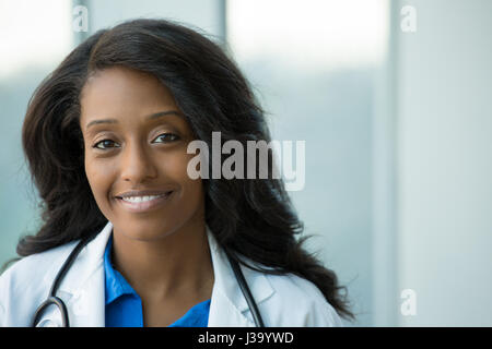 Closeup Portrait von freundlichen, lächelnden zuversichtlich weiblichen Arzt mit Kittel, Stethoskop, Arme gekreuzt. Isolierte Klinik zurück Stockfoto