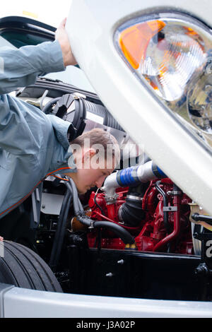 Der professionelle LKW-Fahrer inspizieren seinen schweren Sattelzug, um die korrekte Funktion aller Motorkomponenten zu überprüfen, bevor er zur Auslieferung geht Stockfoto
