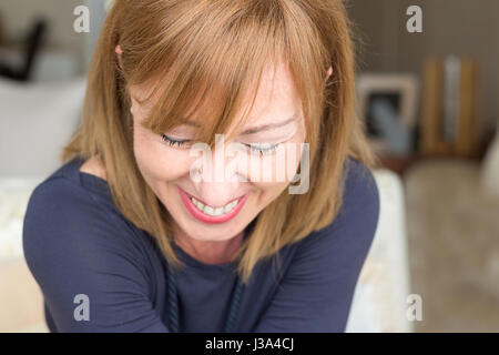Closeup Portrait einer reifen Frau lächelt, schaut nach Hause Hintergrund. Stockfoto