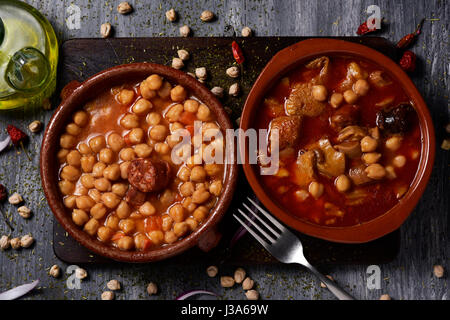 High-Angle Shot von zwei Steingut Schüsseln mit zwei typische spanische Gerichte, Potaje de Garbanzos ein Kichererbsen-Eintopf mit Chorizo und Serrano Schinken auf der le Stockfoto