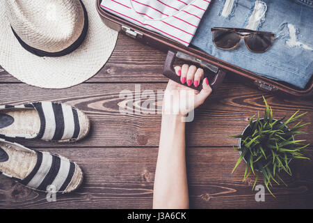 Reisevorbereitungen Konzept auf Holztisch mit offenen Koffer, Kleidung und Zubehör Stockfoto