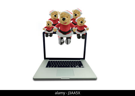 Laptop-Arbeitsplatz und ein Weihnachtsmann Teddy Bär Weihnachten auf weißem Hintergrund isolieren. Stockfoto