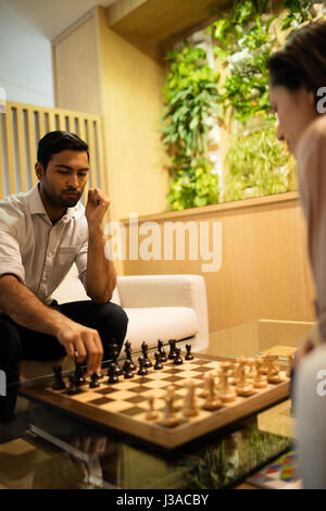 Geschäftsmann, spielt Schach mit Kollegin im Büro Stockfoto
