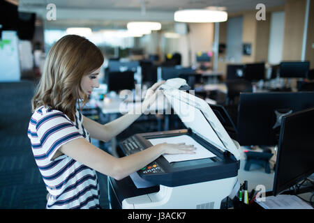 Seitenansicht der Geschäftsfrau mit Kopierer im Büro Stockfoto