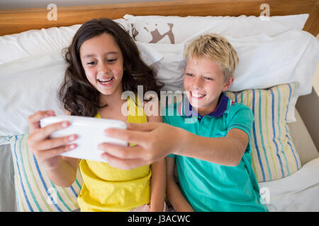 Geschwister unter Selfie auf Handy im Schlafzimmer zu Hause Stockfoto