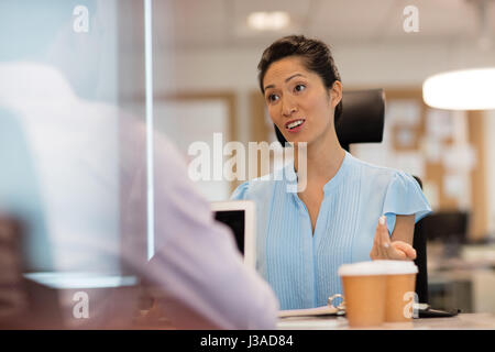 Geschäftsfrau, die Diskussion mit Kollegen im Büro durch Glas gesehen Stockfoto