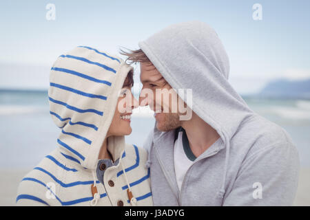 Lächeln, paar tragen Kapuzen Pullover am Strand im winter Stockfoto