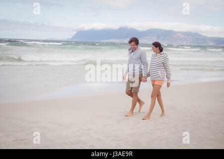 Junges Paar Hand in Hand spazieren am Strand Stockfoto