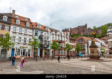 HEIDELBERG, Deutschland - 3. Mai 2013: Passanten am Kornmarkt Square in Heidelberg Altstadt, Deutschland. Madonna-Statue im Vordergrund und Heidelberg cas Stockfoto