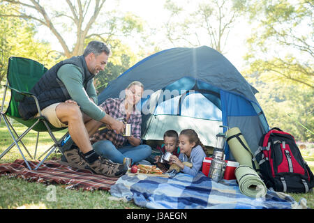 Familie mit Snacks und Kaffee außerhalb des Zeltes auf Campingplatz Stockfoto