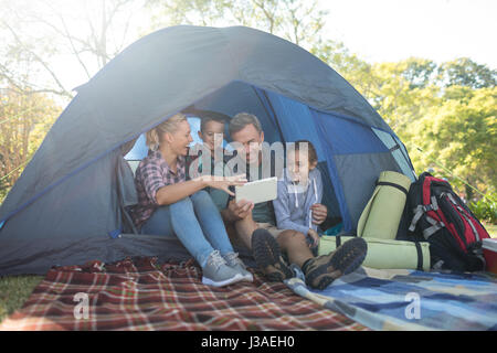 Lächeln, Familie mit Blick auf die digitale Tablet im Zelt Stockfoto
