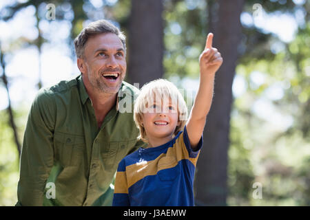 Kleiner Junge zeigt etwas zu fröhlich Vater beim Wandern im Wald Stockfoto