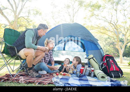 Familie Interaktion mit Snacks außerhalb des Zeltes an Campingplatz Stockfoto