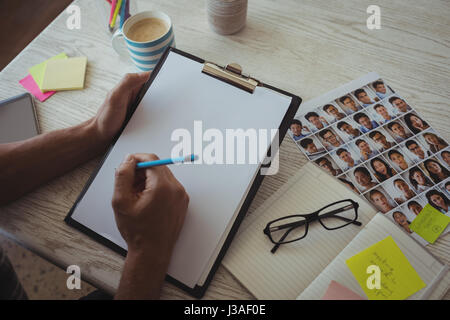 Händen der Foto-Editor schreiben in Zwischenablage an kreativen Schreibtisch beschnitten Stockfoto