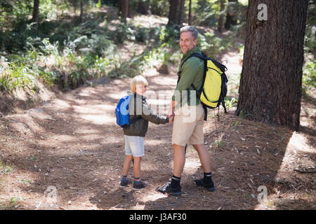 In voller Länge Portrait von lächelnden Vater und Sohn Rucksack beim Wandern im Wald Stockfoto