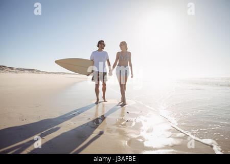 Gesamte Länge der junge Paar Hand in Hand am Strand im sonnigen Tag Stockfoto