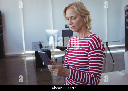 Geschäftsfrau mit Mobiltelefon und stützte sich auf Sofa im Büro Stockfoto